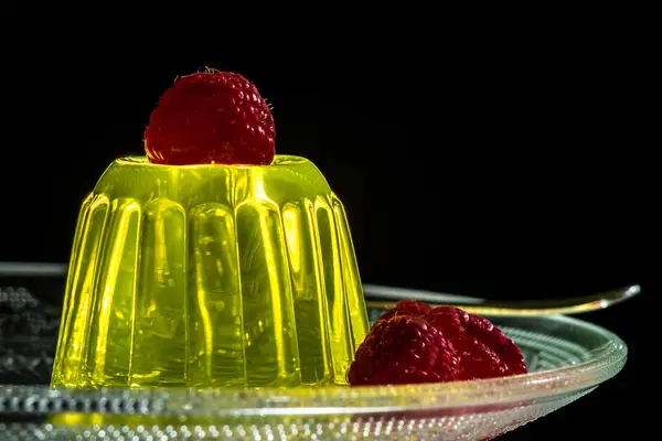 Lemon jelly dessert with raspberries on a glass plate