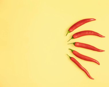 Kırmızı biberler sarı arkaplanda uzanıyor, düz konsept ve kopyalama alanı