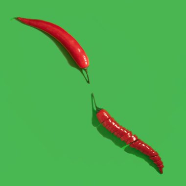 Yeşil arka planda iki kırmızı biber, düz kare kompozisyon.