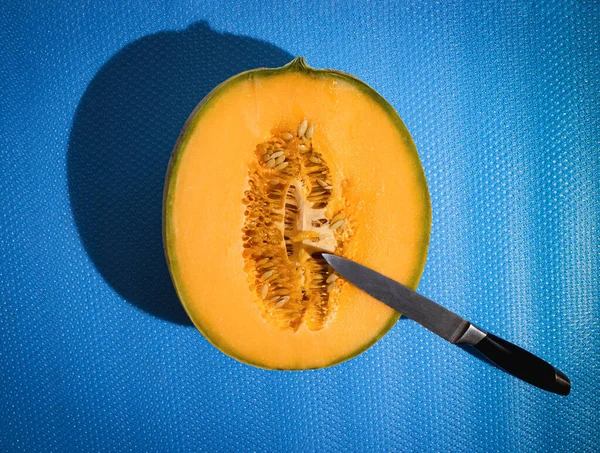 Sliced melon and knife, summer refreshment minimal concept on a blue background