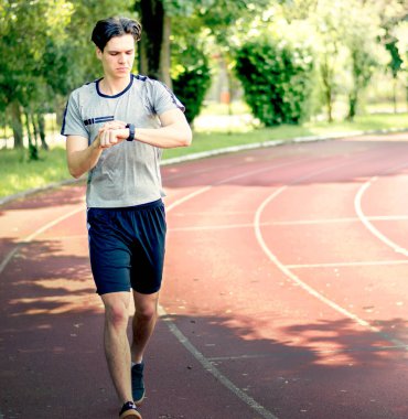 Genç sporcu akıllı saatine bakıyor. Koşu parkurunda iz sürme sonucu. Form kontrolü sonucu..