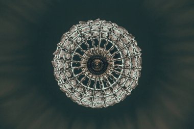 Cyrstal Chandelier karanlık arka planda parlıyor. Işık, izole edilmiş bir avizenin içinden siyah bir zemin üzerinde parlıyor..