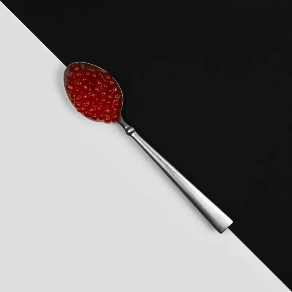 Siyah ve beyaz arka planda kaşıkta kırmızı havyar