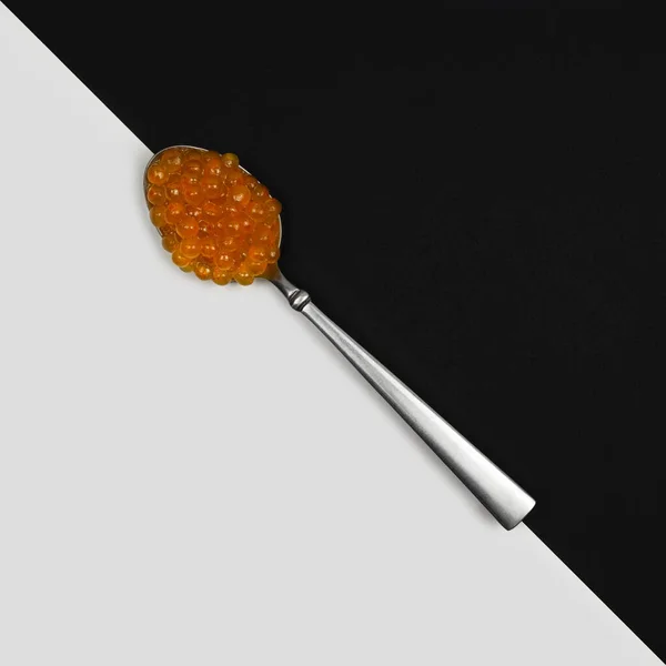 Siyah ve beyaz arka planda kaşıkta kırmızı havyar