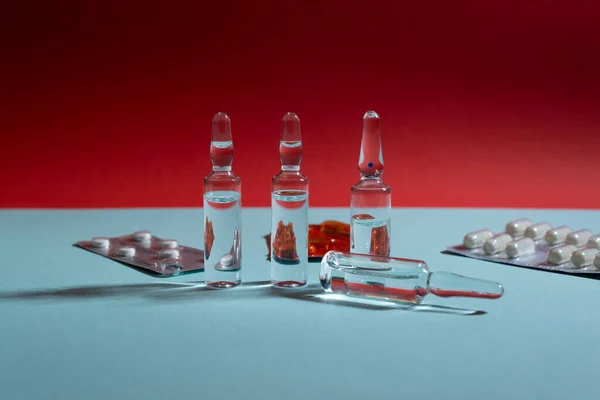 Cam ampuller ve haplar mavi ve kırmızı arka planda su toplamış.