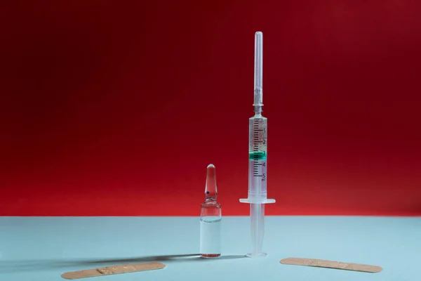 Cam ampul, şırınga ve mavi ve kırmızı arka planda yamalar.
