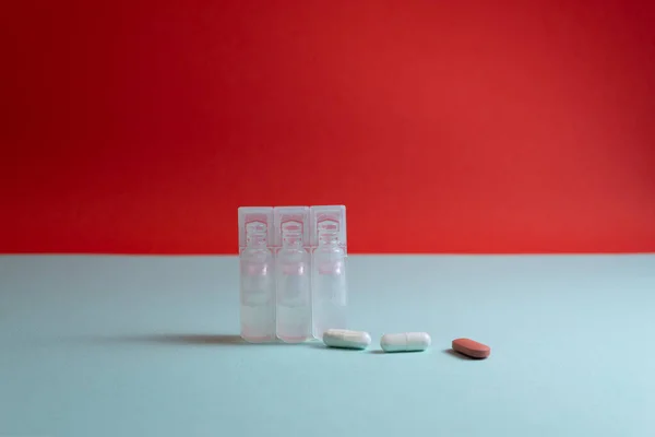Plastik ampuller ve haplar mavi ve kırmızı arka planda