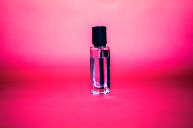 Kırmızı arka planda güzel bir parfüm şişesi.