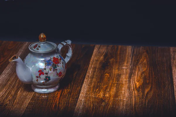 Eski bir yırtık dokunun arka planında bir çaydanlık. Başla. Çay doldurucu için güzel, parlak bir çaydanlık. Ocakta çay demlemek için desenli çaydanlık.