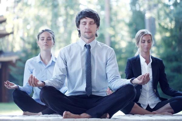 Mensen uit het bedrijfsleven beoefenen van yoga — Stockfoto