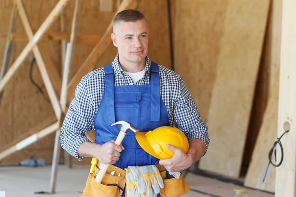 Obrero de la construcción con martillo en la mano y herramientas en la obra — Foto de Stock
