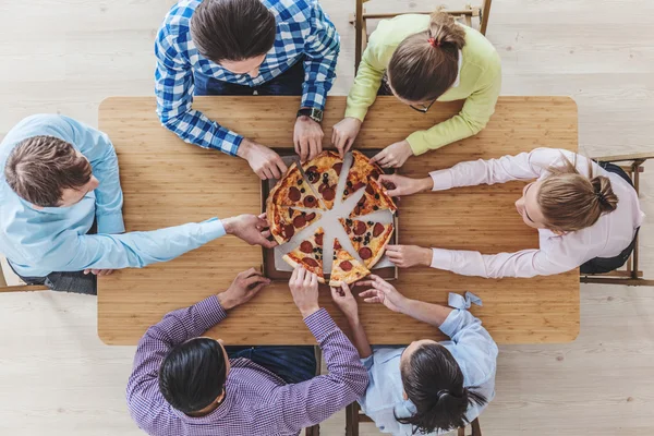 Vrienden handen nemen segmenten van pizza — Stockfoto