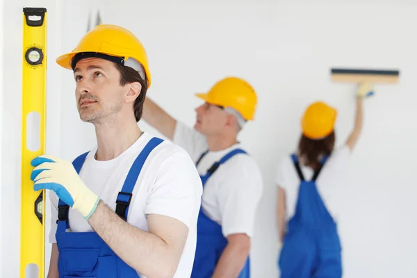 Building teamwork concept - group of smiling builders in hardhats with tools indoors — Stock Photo, Image