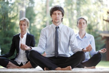 İş adamları parkta yoga yapıyor.