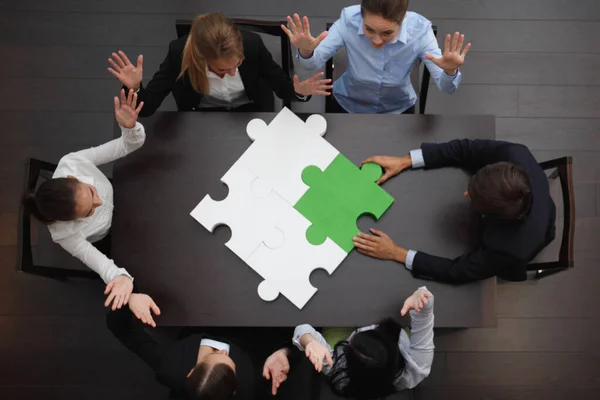ビジネスグループオフィステーブルでジグソーパズルを組み立てる人々 トップビュー チームのサポートとヘルプコンセプト 緑と白の作品 — ストック写真