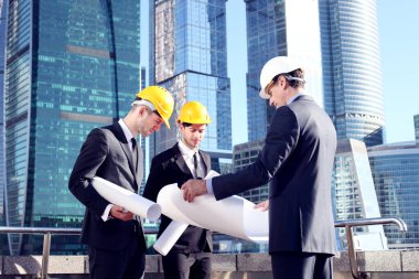 Gökdelenlerin arkaplanındaki planlara sahip mimarlar