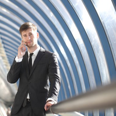 Takım elbiseli genç bir işadamının portresi ofiste duruyor ve telefonla konuşuyor.