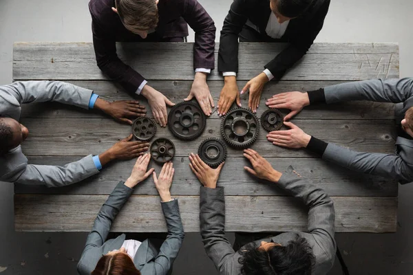 Business people connect gear together at meeting table, success cooperation teamwork concept