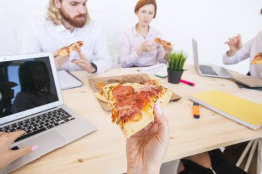 Bir grup iş adamı, bir ofiste birlikte çalışırken ara vermeden pizza yiyorlar.