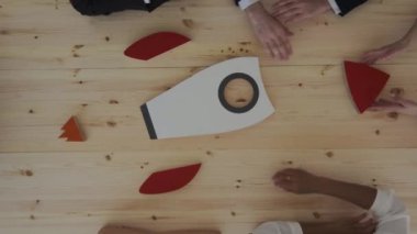 İş adamlarından oluşan bir ekip roketle yüksek riskli hedeflerin sembolü olarak toplantı masasındaki kırmızı hedefi hedef alıyorlar.