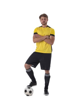 Bir ayağı topun üzerinde duran futbolcu kollarını kavuşturup beyaz arka planda izole bir şekilde duruyor.