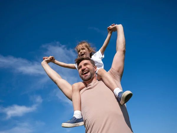 Küçük Kız Babasının Boynunda Oturuyor Mavi Gökyüzü Arka Planında Kollarını — Stok fotoğraf