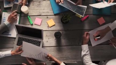 Çeşitli yönetici iş adamları toplantıda iş sonuçlarını tartışıyor, finansal istatistikleri analiz eden çok ırklı işadamları modern ofiste dizüstü bilgisayar ve belgelerle birlikte oturuyorlar
