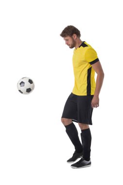 Beyaz arka planda, beyaz tenli futbolcu topa vuruyor.