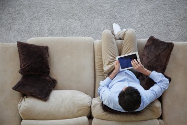 tablet ile kanepede oturan adam