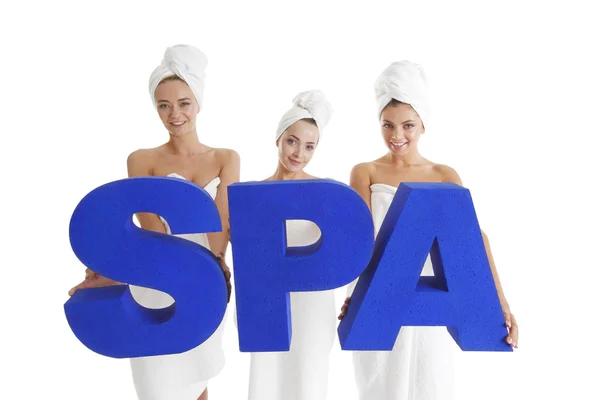 Kvinnor insvept i handdukar holdin SPA bokstäver isolerad på vit bakgrund — Stockfoto