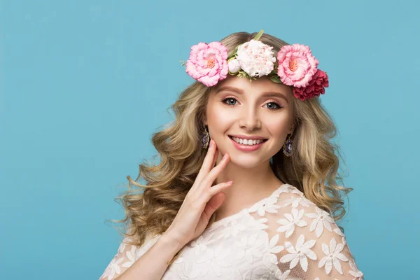 Güzellik Portresi. Çiçek çelenk ile güzel sarışın kadın. Kameraya bakıyor. Saç çok dokunaklı. Üzerinde mavi arka plan izole. Gençlik, mutluluk kavramı