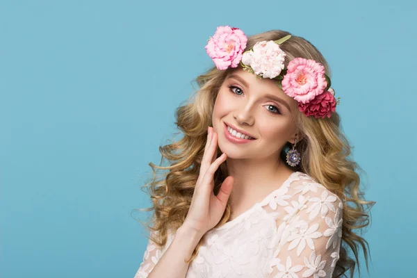 Güzellik Portresi. Çiçek çelenk ile güzel sarışın kadın. Kameraya bakıyor. Saç çok dokunaklı. Üzerinde mavi arka plan izole. Gençlik, mutluluk kavramı