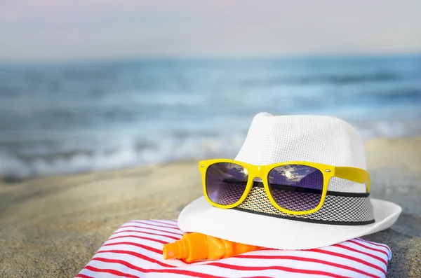 Hatt och solglasögon på stranden. — Stockfoto