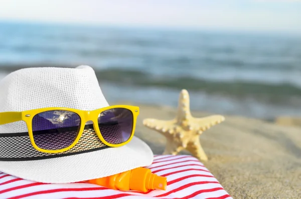 Hatt och solglasögon på stranden. — Stockfoto
