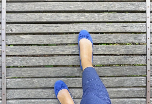 Feet in shoes on a wooden bridge.