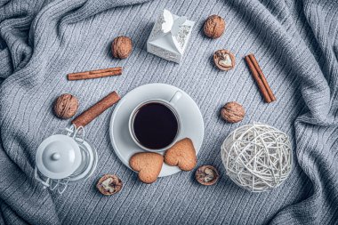 Beautiful plaid, a cup with coffee and cookies on a table with candles.