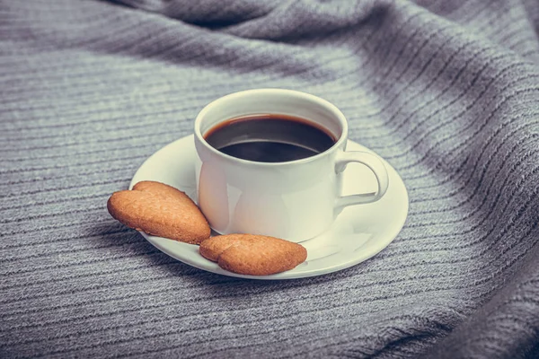 A cup of coffee on a table covered with a blanket. — Photo