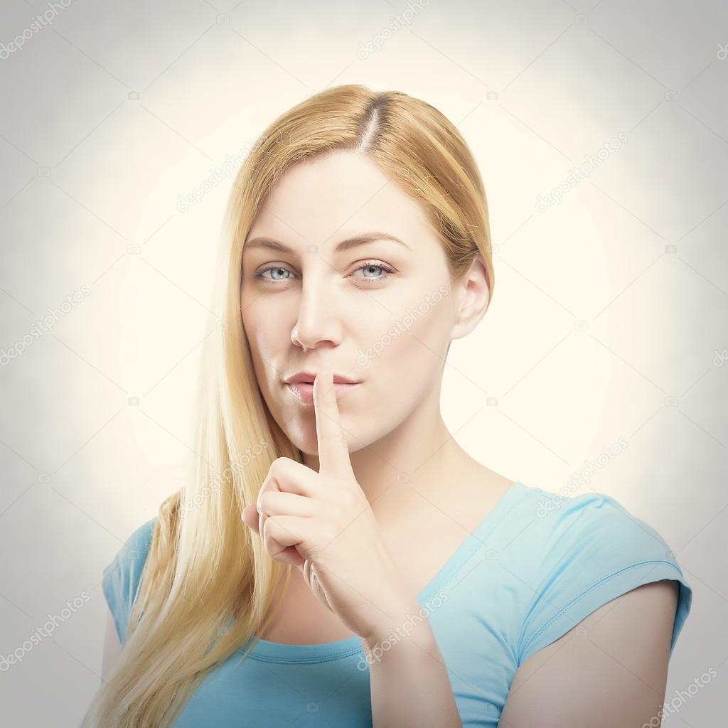 Blonde holding a finger to her mouth. 