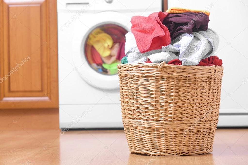 Basket with laundry and washing machine.