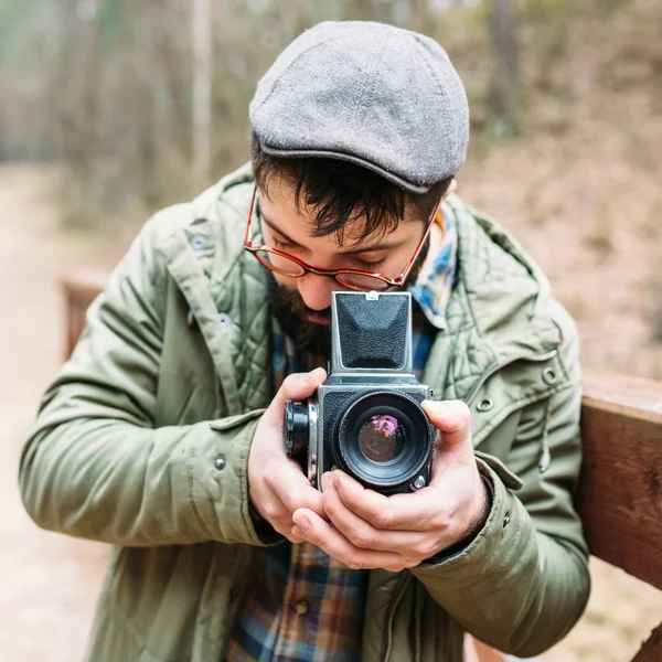 Ung man skäggig med filmen photocamera i skogen — Stockfoto