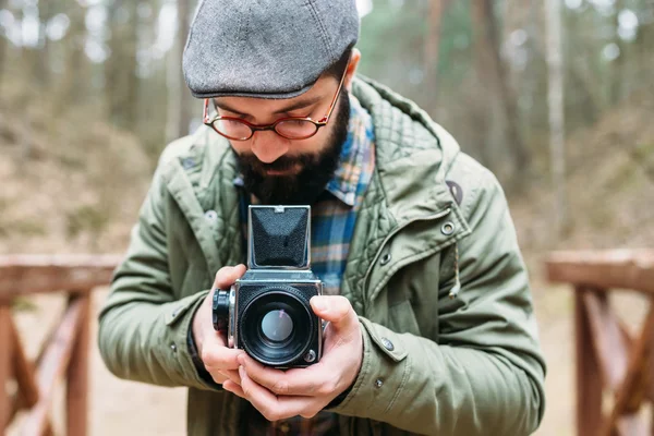 Genç adam ormandaki film photocamera ile sakallı
