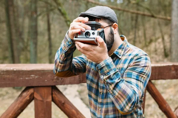 Ung man skäggig med filmen photocamera i skogen — Stockfoto