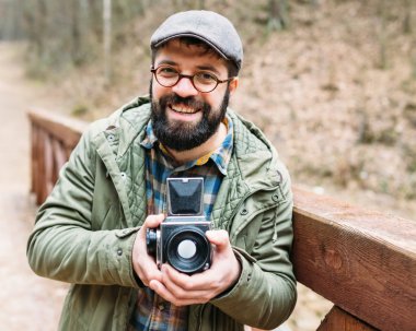 Genç adam ormandaki film photocamera ile sakallı