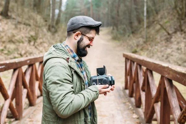 Ung man skäggig med filmen photocamera i skogen — Stockfoto