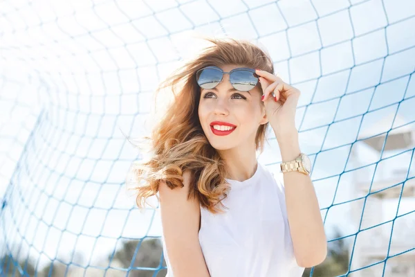 Menina na moda posando contra um fundo de futebol azul g — Fotografia de Stock