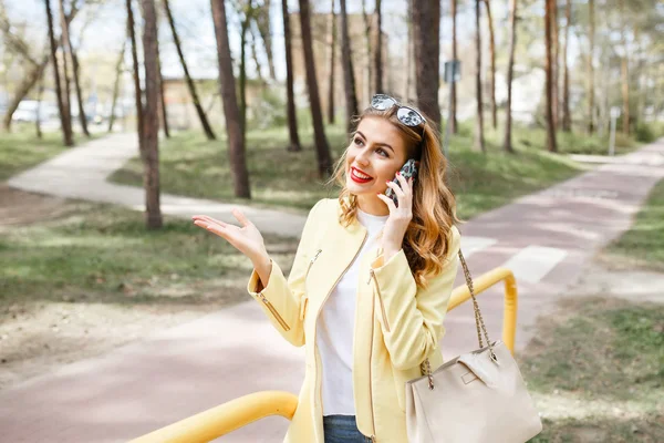 Beautiful, stylish girl on a sunny day in the park talking on th — Stock Photo, Image