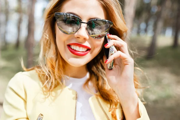 Schöne, stylische Mädchen an einem sonnigen Tag im Park im Gespräch auf th — Stockfoto