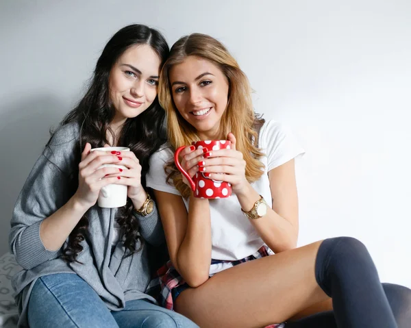 Dos chicas hermosas jóvenes riendo y posando con tazas e inha —  Fotos de Stock