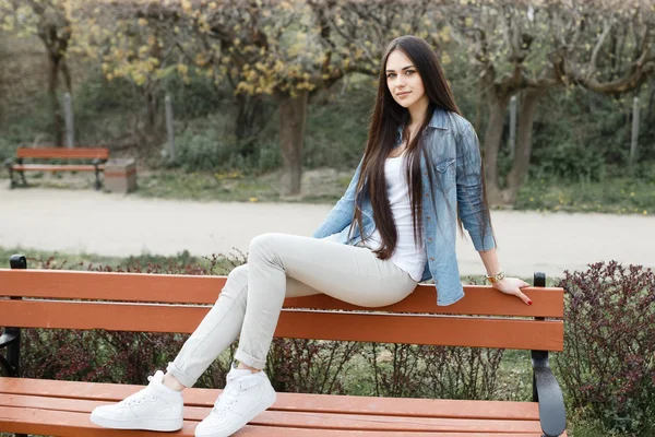 Menina bonita em um banco no parque — Fotografia de Stock