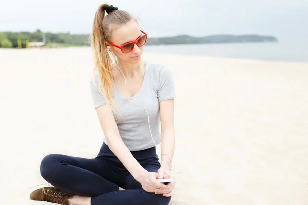 Sports girl on the beach wearing sunglasses — Stock Photo, Image